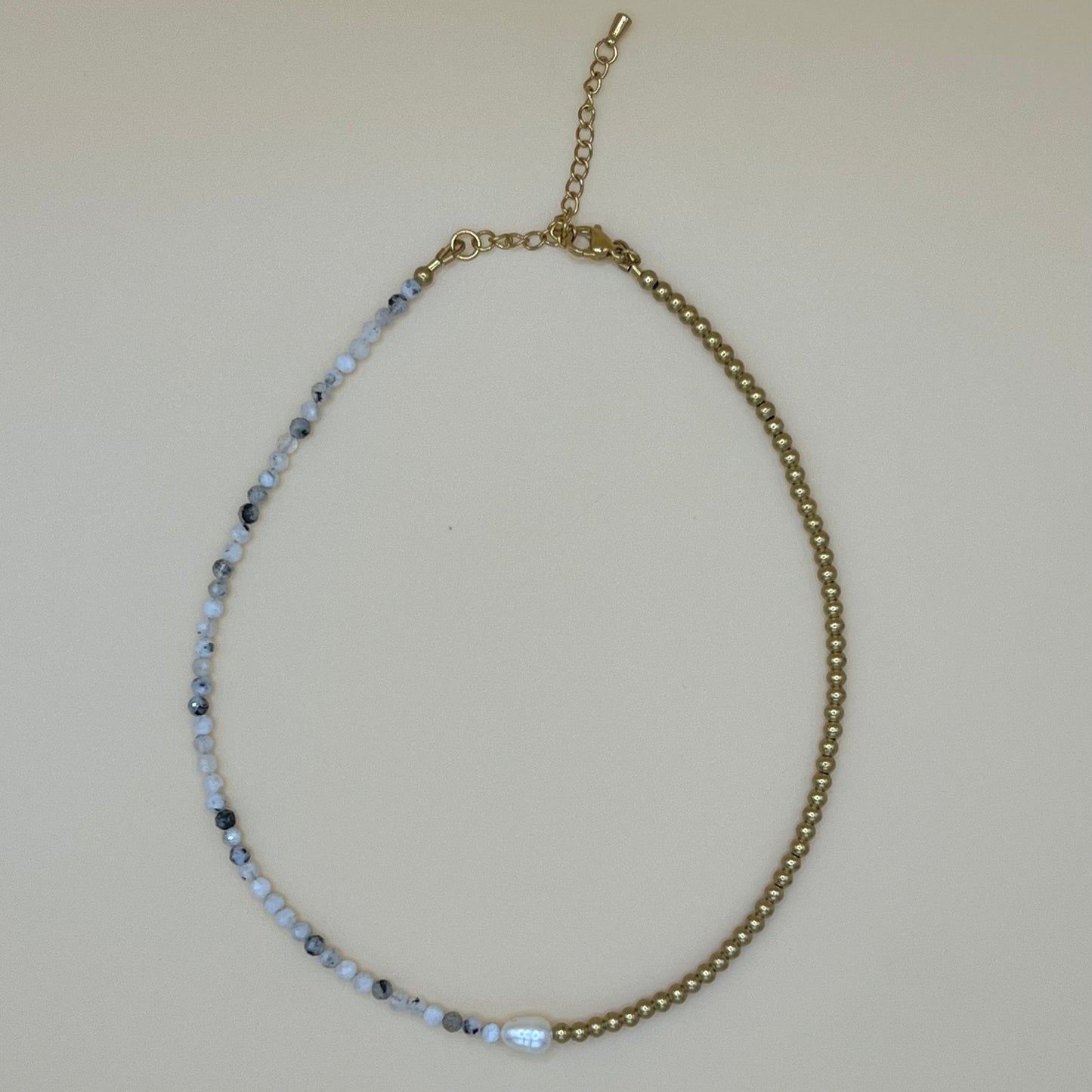 Flatlay of dainty pearl and gemstone choker necklace with adjustable gold clasp and natural beaded detailing on neutral background