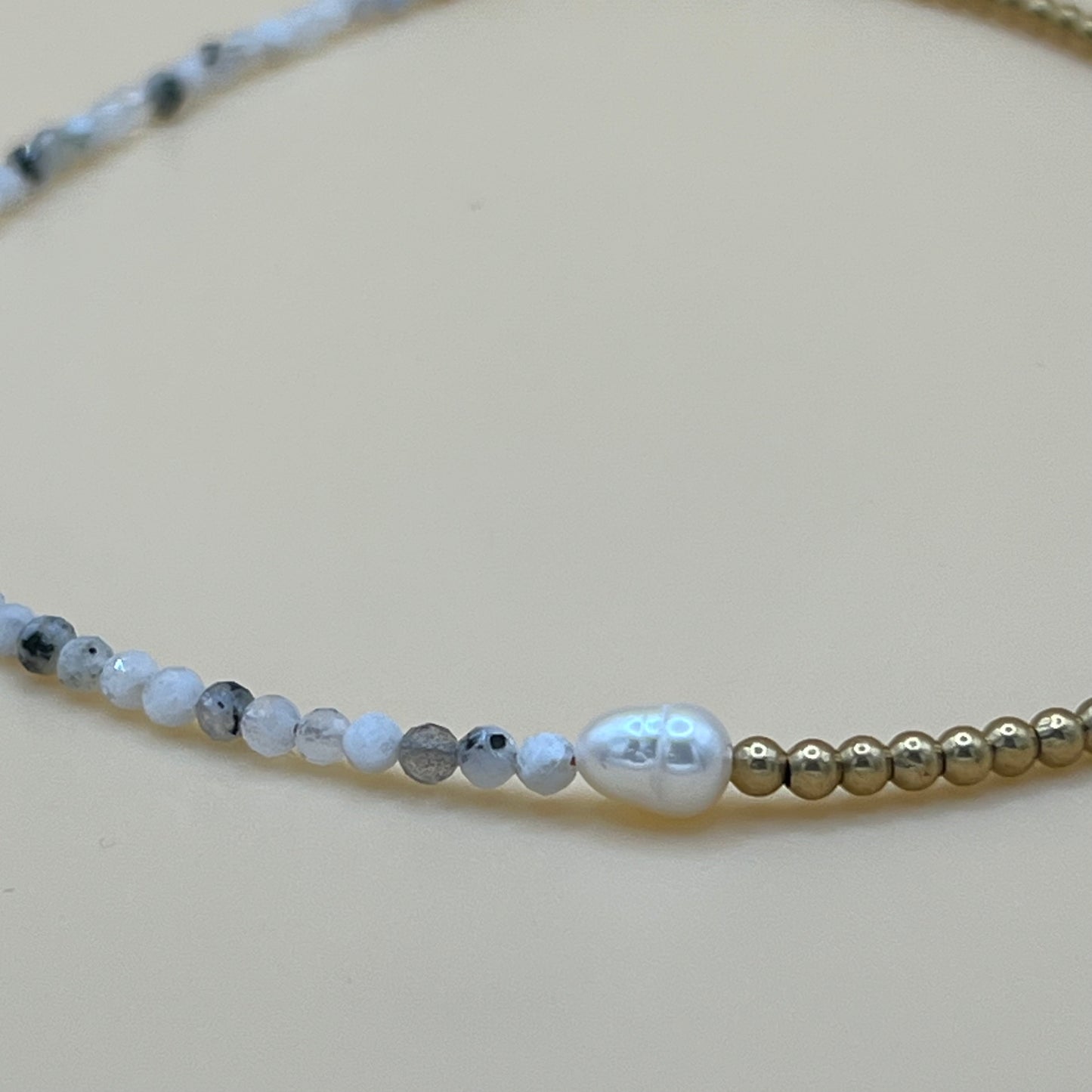 Focal close-up of freshwater pearl and faceted gemstone beaded necklace with brass accents, highlighting texture and contrast on a neutral background