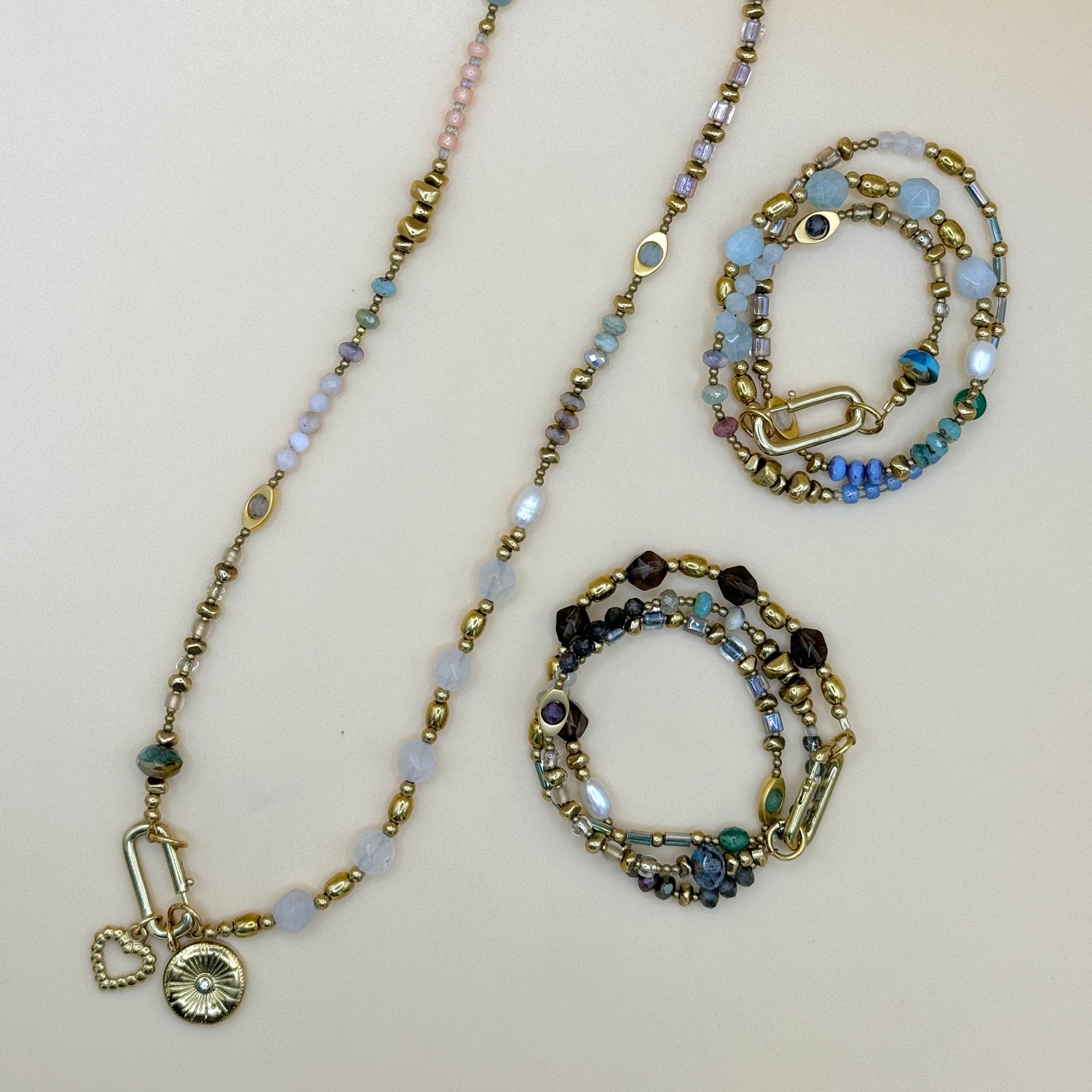 Flat lay of May & Moon’s Everything Set, featuring a handmade beaded necklace and two wrap bracelets crafted with pearls, fire-polished Czech glass, gemstones, and gold accents in charm-ready, stackable boho style.