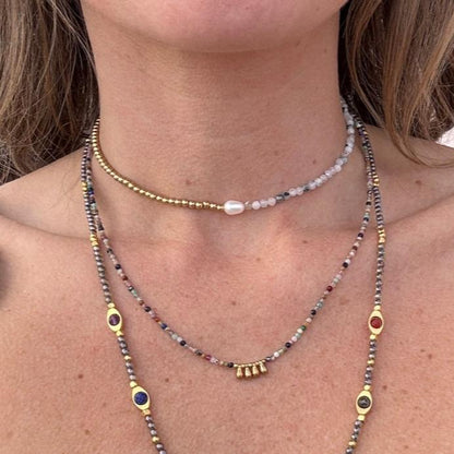 Layered boho necklaces  Lennon worn by a woman, featuring handmade beaded designs with gold accents and colorful gemstones by May & Moon.