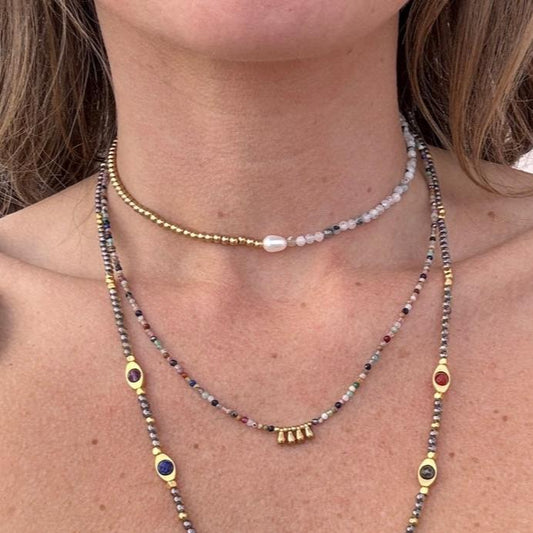 Layered boho necklaces  Lennon worn by a woman, featuring handmade beaded designs with gold accents and colorful gemstones by May & Moon.